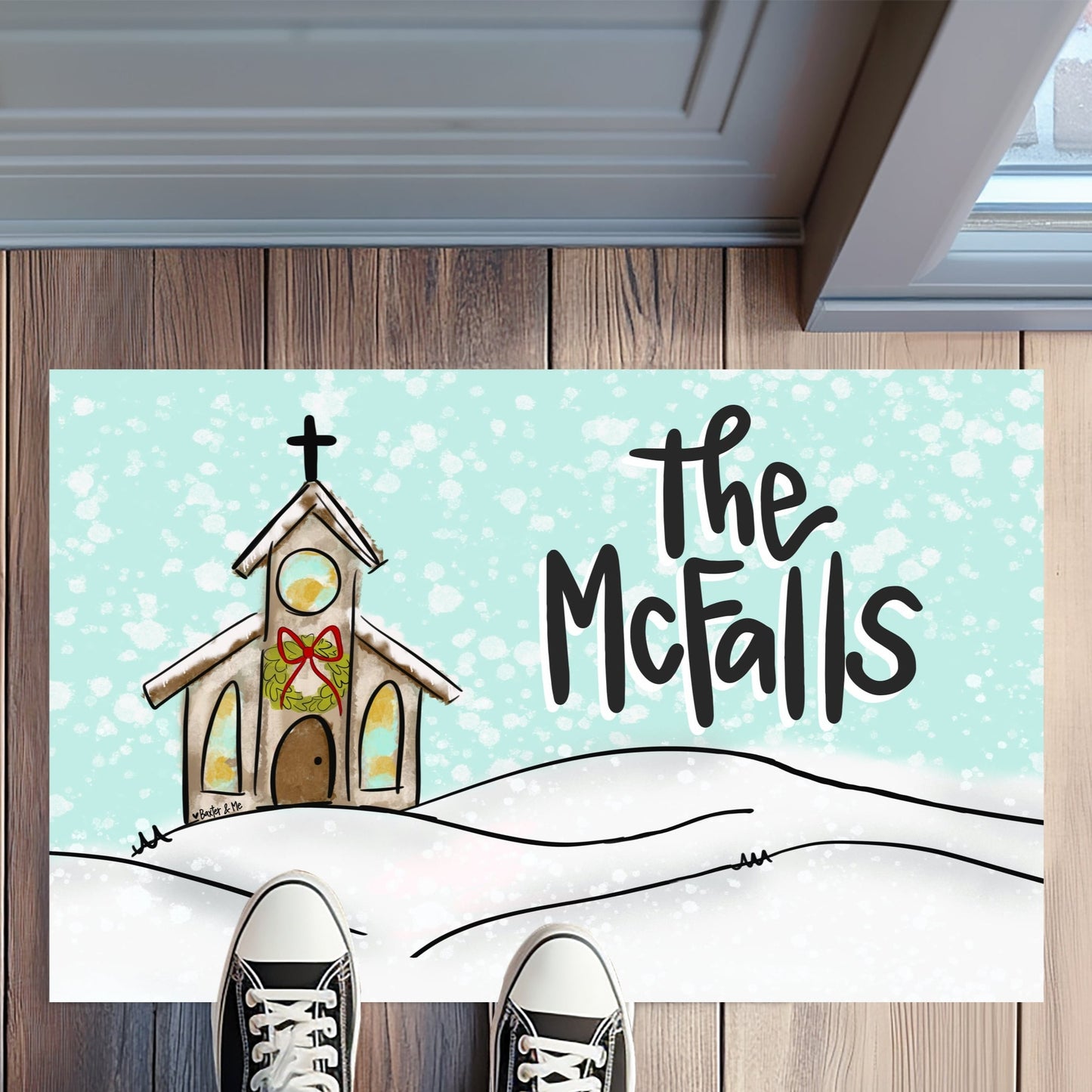 Doormat with a church design and 'The McFalls' text on a wooden floor.