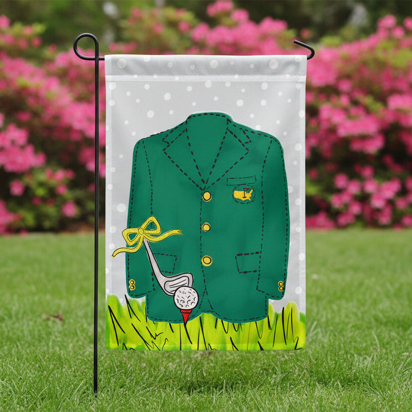 Garden flag with a green blazer, golf club, and ball on a polka dot background featured in a yard with pink azaleas