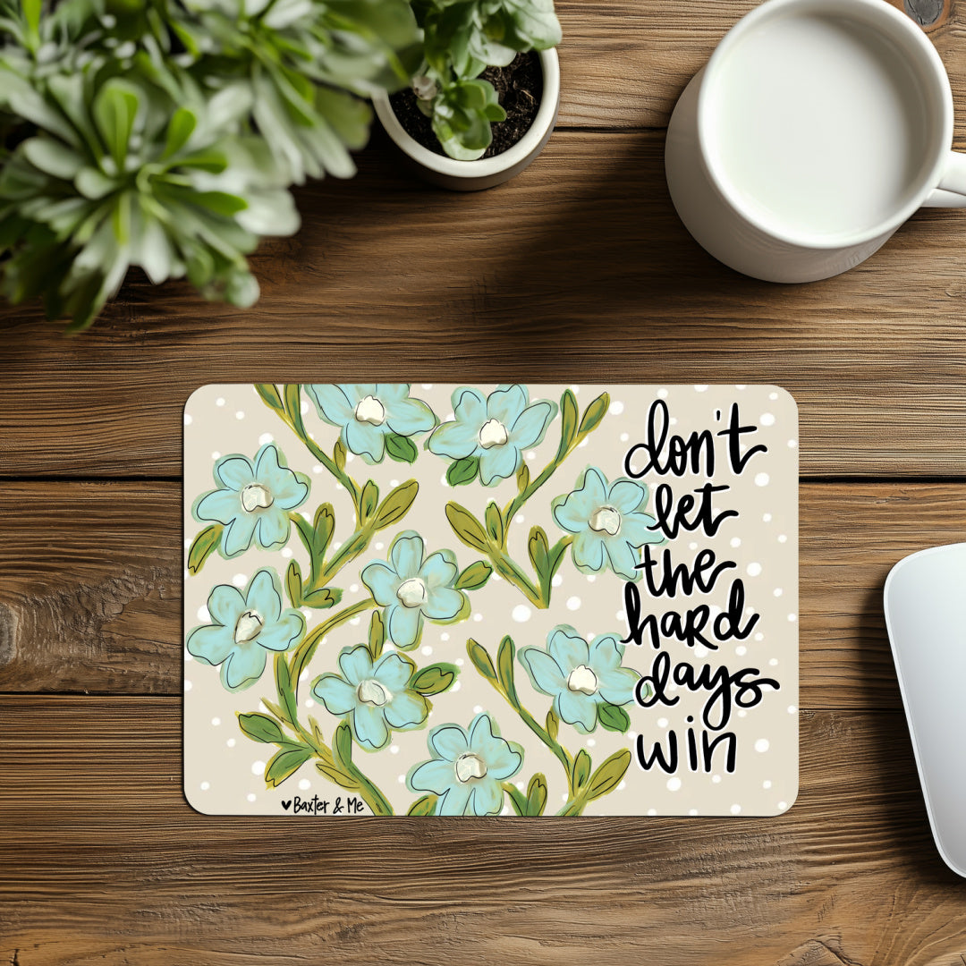 Floral placemat with motivational quote on a wooden table with a plant and mug.