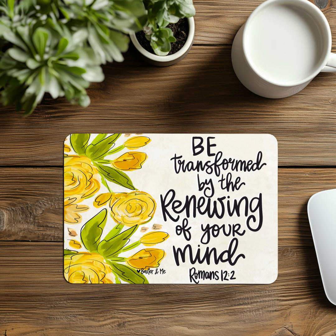 Decorative mat with floral design and motivational quote on a wooden surface with plants and a mug.