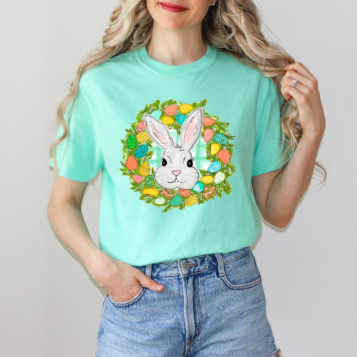 Person wearing a light blue t-shirt with a bunny and Easter eggs design.