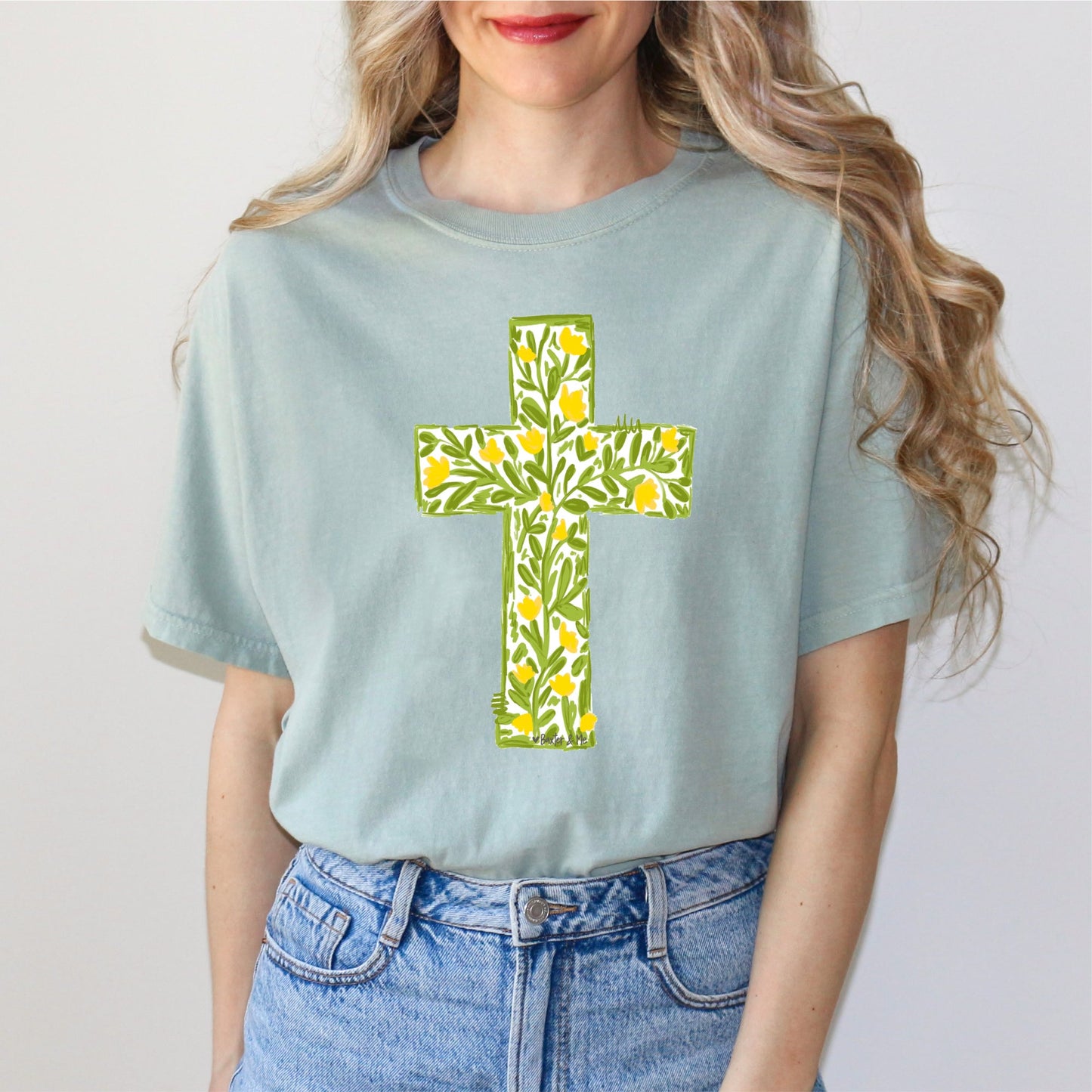 Light blue t-shirt with a floral cross design worn by a person on a plain background