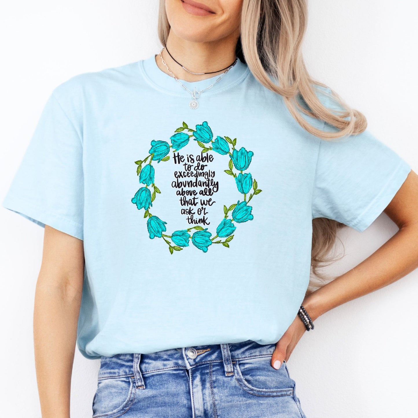 Person wearing a light blue t-shirt with a floral design and text.
