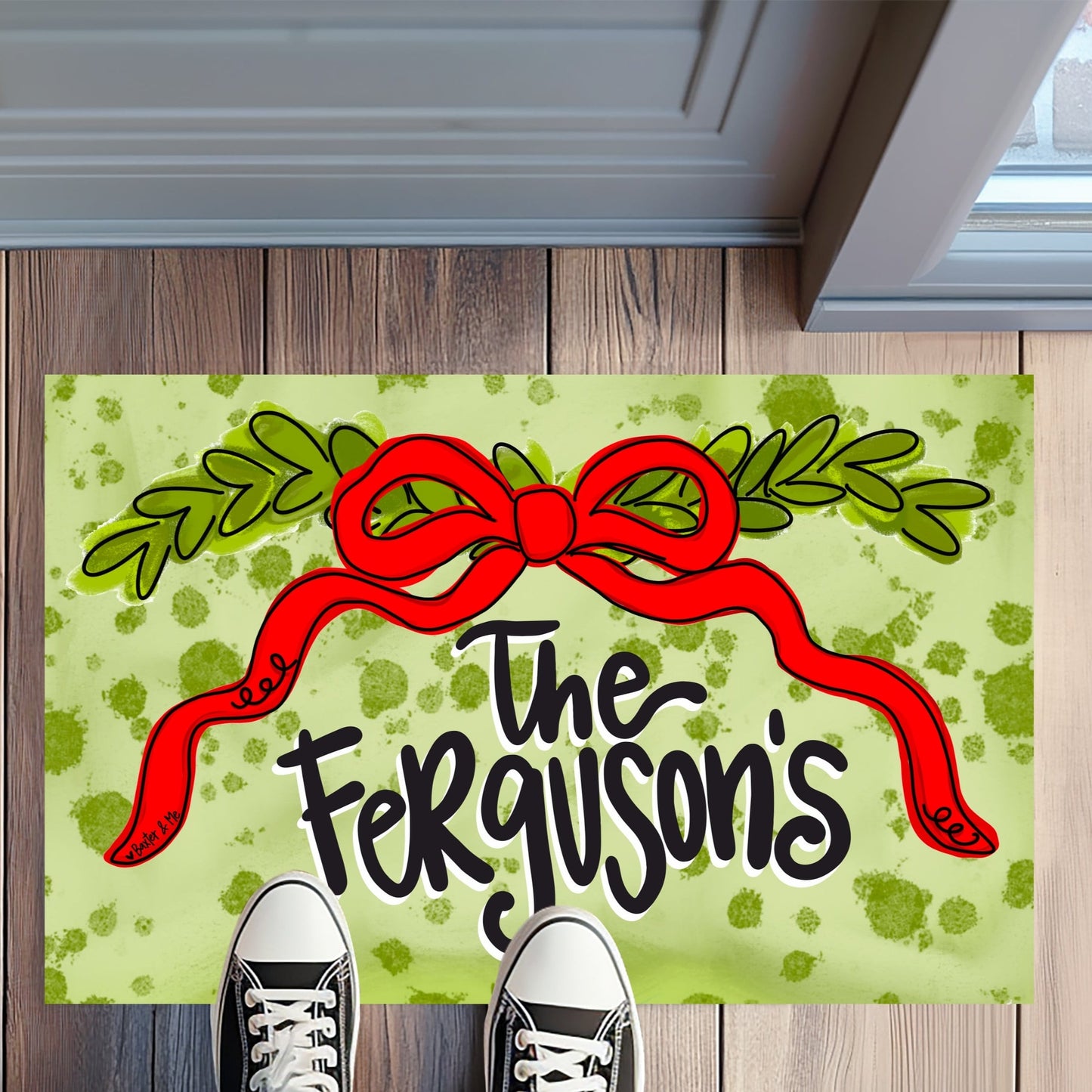 Personalized doormat with a red bow and 'The Ferguson's' text on a wooden floor.