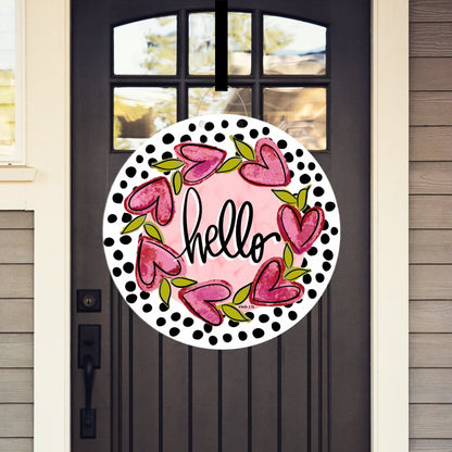 Decorative door hanger with pink hearts and 'hello' text on a black door.