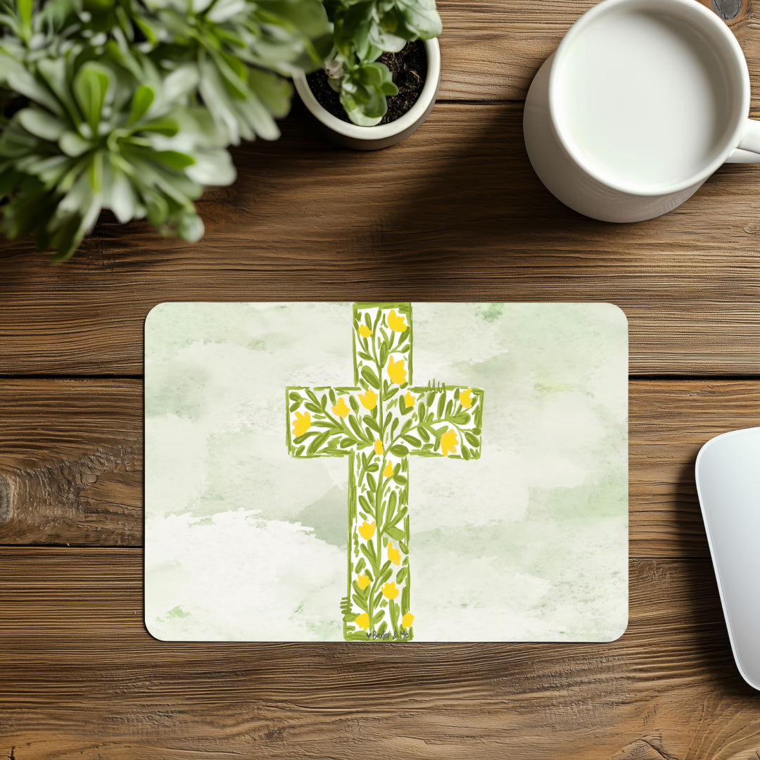 Placemat with floral cross design on a wooden table with a cup of coffee and plant.