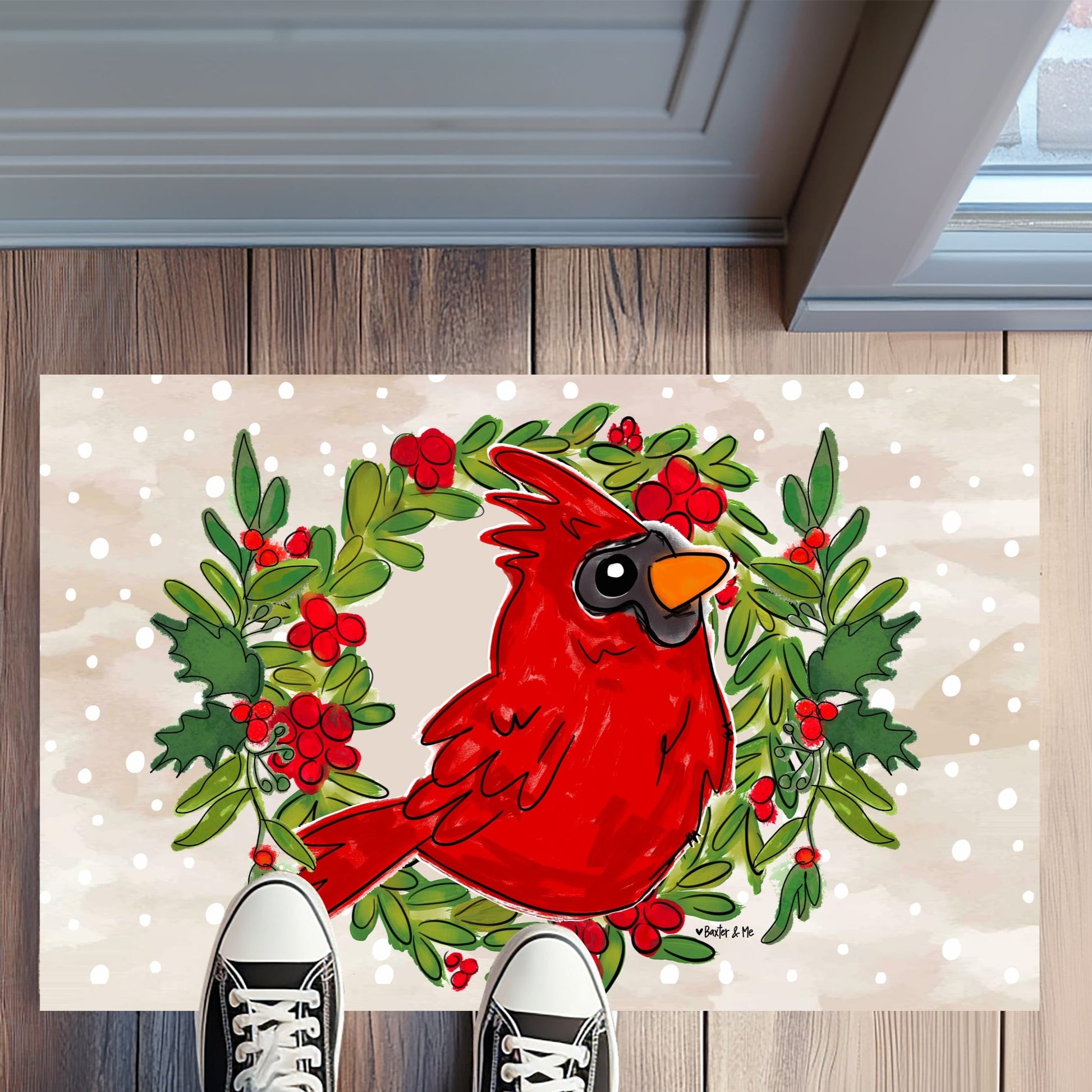 Decorative doormat with a red cardinal and wreath design on a wooden floor.